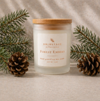 Brimstage Botanicals Forest Embers candle with lid sat next to pine cones and sprigs of freshly cut pine